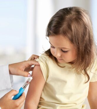 Female nurse giving an arm injection to a child.