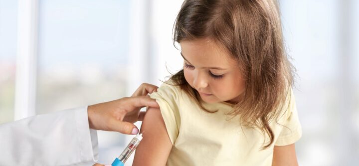 Female nurse giving an arm injection to a child.