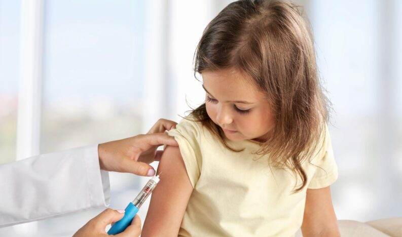 Female nurse giving an arm injection to a child. Female nurse giving an arm injection to a child.
